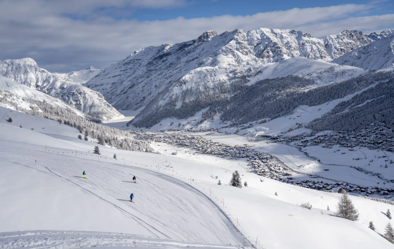 Skiërs op een brede piste in Carosello 3000 met uitzicht op het dal