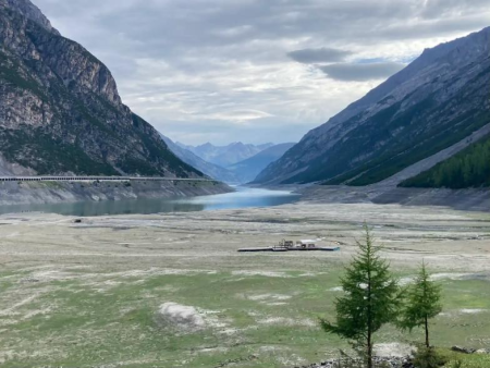 Uitgestrekte, deels drooggevallen vlakte bij het stuwmeer met bergen aan weerszijden – Rondwandeling om het Lago di Livigno, Livigno