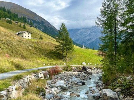 Beek met keien langs een weggetje en een wit berghuisje – Val Federia en de Chiesetta dell'Addolorata, Livigno