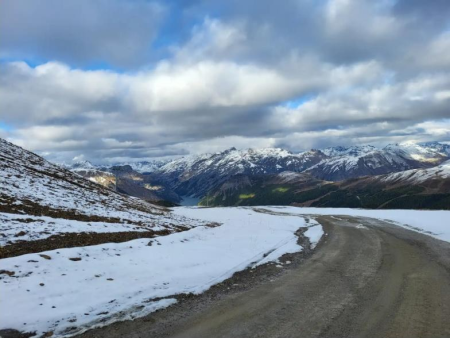 Besneeuwd dal met een bevroren beek onder een wolkenlucht – Monte delle Rezze (2.858 m), Livigno